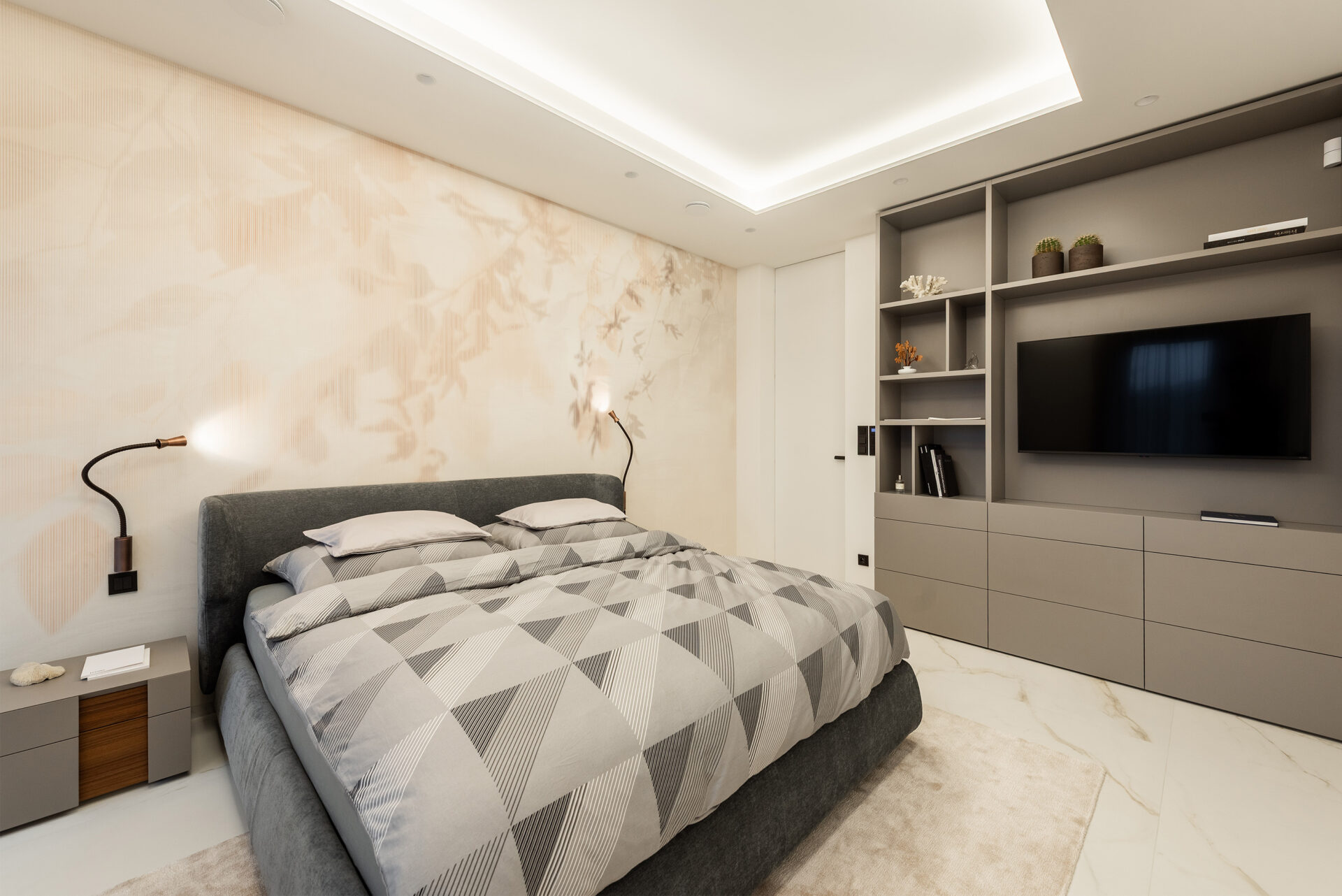 Světlá ložnice s&nbsp;čalouněnou postelí, jemným kamenným dekorem a&nbsp;vestavěným nábytkem. Inspirace z&nbsp;realizace REMY Design.